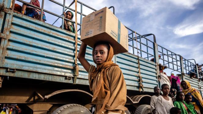 A Sudanese girl who have fled from the war in Sudan with her family carry a box with some of her belongings after arriving at a Transit Centre for refugees in Renk, on February 13, 2024.